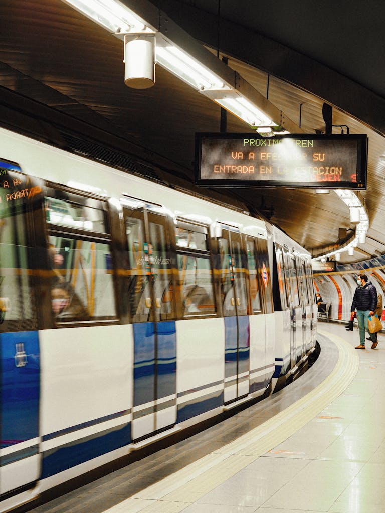 A blurred subway train rushes through a Madrid station, capturing urban energy.