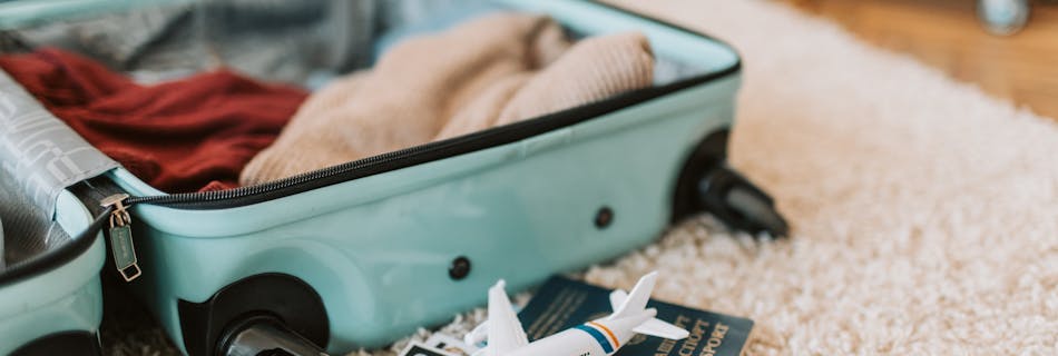 Close-up of an open suitcase with travel essentials like passport and tickets, ready for a journey.