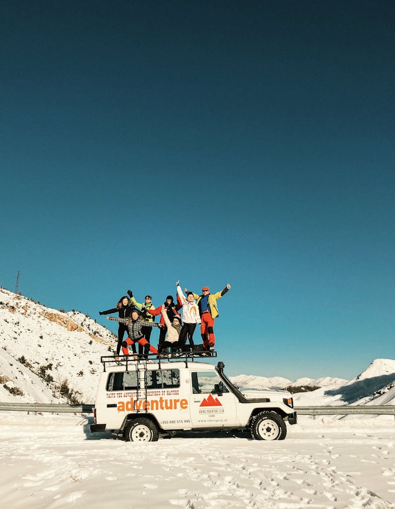 A group of friends atop a 4x4 vehicle exploring snowy mountains in Tirana, Albania. If you're a female looking to solo travel in Europe, you can join tons of groups.