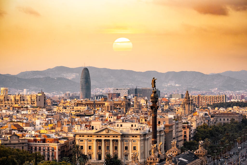 A stunning sunset view of the Barcelona skyline showcasing iconic landmarks and a warm, golden hour glow. A great place for Female Solo travellers to visit in Europe.