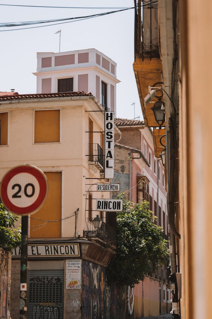 Sunny narrow alley with Hostal signage and urban architecture in focus.